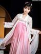 A woman in a pink and white hanbok is posing for a picture.