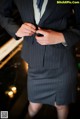 A woman in a business suit is adjusting her tie.