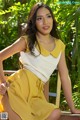 A woman in a yellow dress sitting on a wooden bench.