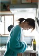 A woman standing in a kitchen next to a stove.