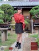 A woman in a red shirt and black skirt posing for a picture.