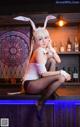 A woman in a bunny costume sitting on a bar.