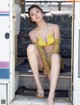 A woman in a yellow bikini sitting on the steps of a bus.