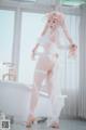 A woman in a white lingerie standing next to a bathtub.