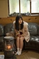 A woman sitting on a couch next to a heater.