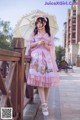 A woman in a pink dress holding an umbrella.