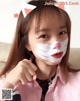 A young girl with a cat face paint on her face.
