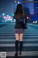 A woman in a school uniform is walking across the street.