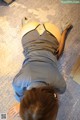 A woman laying on the floor with her back to the camera.