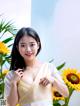 A woman in a white dress posing in front of sunflowers.