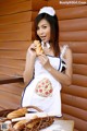A woman in an apron holding a piece of bread.